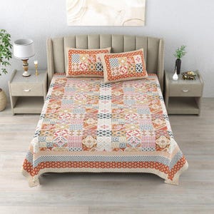 Könnte beinhalten: Ein Bettlaken und zwei passende Kissenbezüge mit einem mehrfarbigen Patchwork-Muster aus geometrischen und floralen Kacheln in Orange-, Blau- und Weißtönen. Das Bettwäsche-Set ist auf einem Bett mit einem hohen, hellen Polsterkopfteil zu sehen.