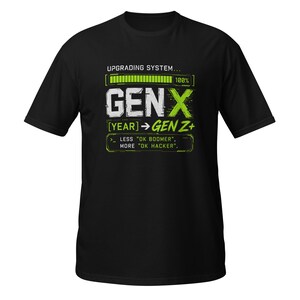 Può includere: Una t-shirt nera a maniche corte con una stampa grafica in bianco e verde lime. Il design include una barra di caricamento con la scritta UPGRADING SYSTEM, il testo GEN X, [YEAR] -> GEN Z+ e la frase LESS OK BOOMER, MORE OK HACKER.