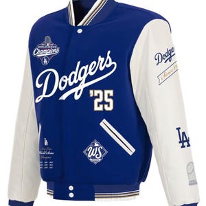 Puede incluir: Una chaqueta varsity azul real y blanca con el logotipo de los Dodgers, el texto '25' y bordado 'World Series Champions'. Las mangas son blancas con puños a rayas azules y doradas. Incluye gráficos 'WS 2025' y texto sobre la historia del equipo.