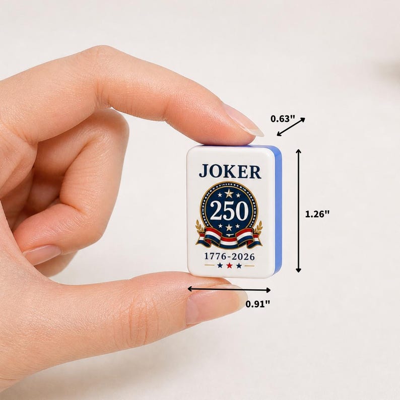 May include: A rectangular white tile with blue edges featuring the text JOKER at the top, a central circular emblem with the number 250, and the text 1776-2026 below. Dimensions are 1.26 inches in height, 0.91 inches in width, and 0.63 inches in depth.