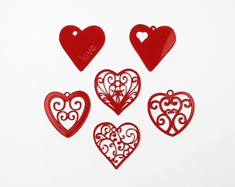 May include: Six red heart-shaped ornaments with different designs. One heart has the word "love" inscribed on it. Two hearts have a filigree design. Three hearts are solid.