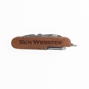 May include: A brown wooden pocket knife with a silver blade and a keychain. The knife is engraved with the name "BEN WEBSTER".