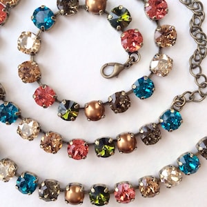 May include: A multi-strand necklace with a variety of colored crystals and pearl accents. The necklace features a mix of teal, brown, green, and coral colored crystals.