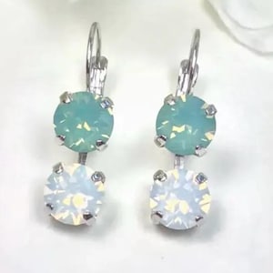 May include: A pair of silver dangle earrings with two round stones. The top stone is a light blue opal and the bottom stone is a white opal.