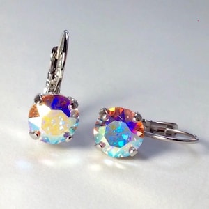 May include: A pair of leverback earrings with iridescent, round-cut crystals. The crystals display a spectrum of colors, including yellow, orange, blue, and purple. The earring settings and leverbacks are silver-toned metal.