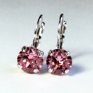 May include: A pair of silver hoop earrings with pink crystal stones.