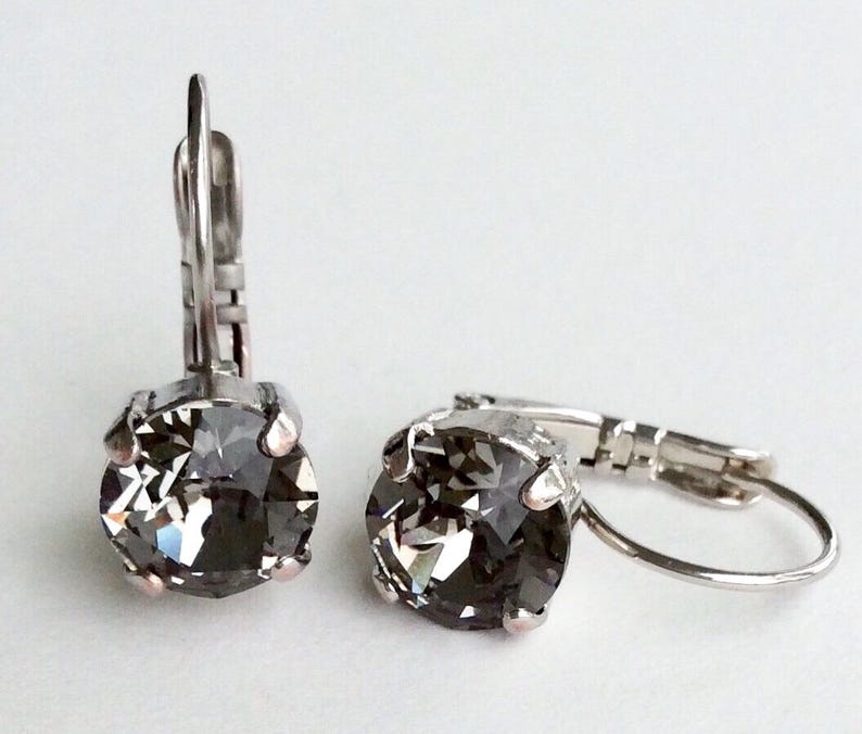 May include: A pair of silver hoop earrings with a dark gray crystal in the center of each hoop.
