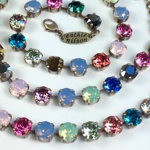May include: A multi-coloured crystal necklace with a silver clasp and a tag that reads "Cathie Nilsson".