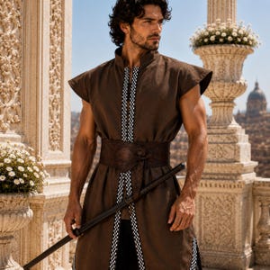 May include: A brown sleeveless tunic featuring a high collar and a vertical front opening trimmed with a black and white checkered pattern. The garment is cinched at the waist with a wide, dark brown textured belt and is paired with a black staff.