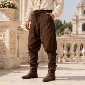 May include: Dark brown trousers featuring a high-waisted design with a drawstring closure, loose-fitting legs, and fitted lower sections that lace up at the sides. The pants are paired with brown leather boots that reach the mid-calf area.