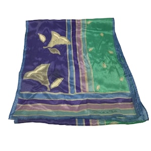 May include: A rectangular scarf featuring a split design of deep purple and bright green. The purple section displays stylized beige floral motifs, while the green section has small beige teardrop shapes. It includes striped borders and the text Oscar de la Renta.