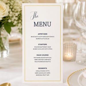 May include: A vertical rectangular menu card with a gold border on a white background. The text reads The MENU, APPETIZER, BRUSCHETTA WITH HEIRLOOM TOMATO, BURRATA & FIG SALAD, STARTERS, ROASTED BUTTERNUT SOUP, SEARED SCALLOPS WITH CITRUS, MAIN COURSE, PAN-SEARED SALMON WITH DILL, HERB-CRUSTED LAMB RACK, WILD MUSHROOM RISOTTO, DESSERTS, VANILLA PANNA COTTA, DARK CHOCOLATE TORTE, SEASONAL FRUIT TART.