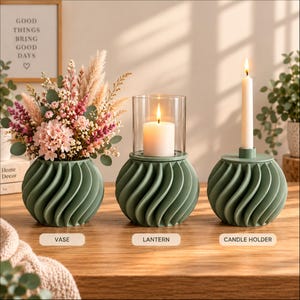 Puede incluir: Tres objetos de color verde salvia con textura acanalada en espiral: un florero con flores secas rosas y beige, un farol de cristal con una vela de pilar blanca y un portavelas con una vela blanca larga y delgada.