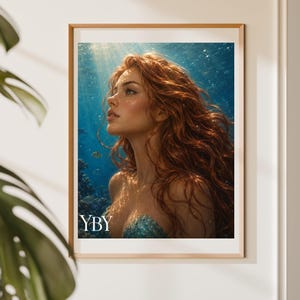 May include: A framed wall art print featuring a portrait of a person with long, wavy red hair underwater. The subject is looking upwards towards the surface light, surrounded by blue water, coral, and small fish. The text YBY is in the corner.