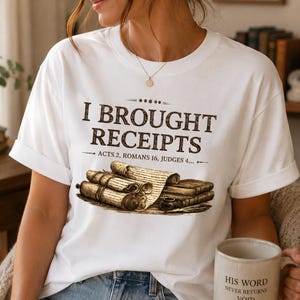 May include: A white t-shirt featuring the brown text I BROUGHT RECEIPTS, ACTS 2, ROMANS 16, JUDGES 4, and an illustration of antique scrolls and a pipe. The design is centered on the chest, showcasing a detailed graphic of rolled parchment documents.