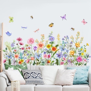May include: A wall decal set featuring a vibrant meadow of wildflowers in shades of pink, orange, yellow, blue, and purple, interspersed with green foliage, butterflies, and dragonflies, arranged in a horizontal garden-like composition.
