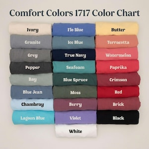 K&ouml;nnte beinhalten: Eine Comfort Colors 1717 Farbkarte mit achtundzwanzig gefalteten T-Shirts in einem Raster. Jedes T-Shirt ist mit seinem spezifischen Farbnamen beschriftet, darunter Ivory, Flo Blue, Butter, Granite, Ice Blue, Terracotta, Grey, True Navy, Watermelon, Pepper, Seafoam, Paprika, Bay, Blue Spruce, Crimson, Blue Jean, Moss, Red, Chambray, Berry, Brick, Lagoon Blue, Violet, Black und White.