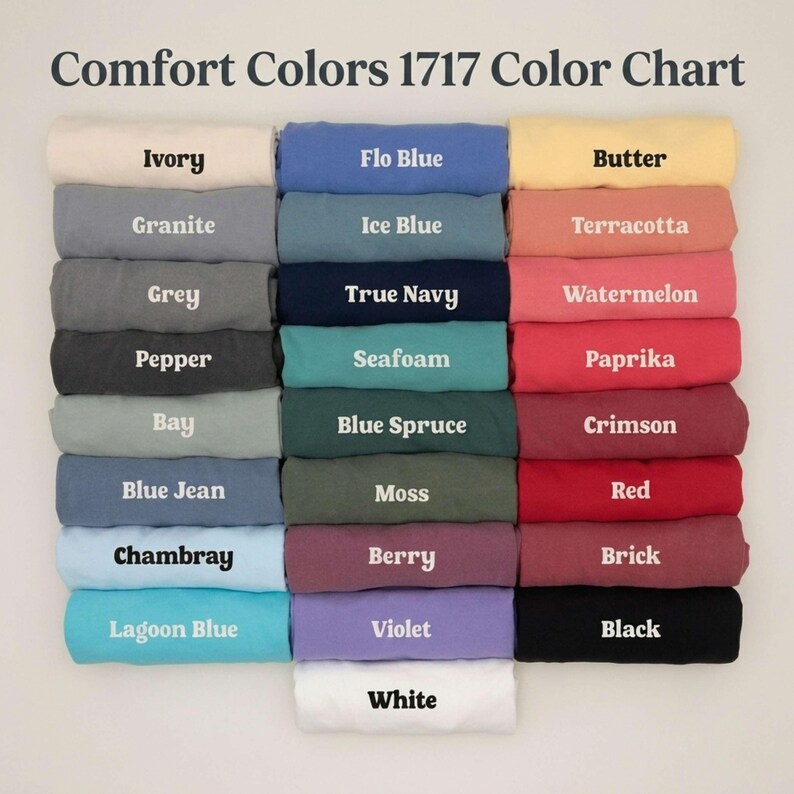 K&ouml;nnte beinhalten: Eine Comfort Colors 1717 Farbkarte mit achtundzwanzig gefalteten T-Shirts in einem Raster. Jedes T-Shirt ist mit seinem spezifischen Farbnamen beschriftet, darunter Ivory, Flo Blue, Butter, Granite, Ice Blue, Terracotta, Grey, True Navy, Watermelon, Pepper, Seafoam, Paprika, Bay, Blue Spruce, Crimson, Blue Jean, Moss, Red, Chambray, Berry, Brick, Lagoon Blue, Violet, Black und White.