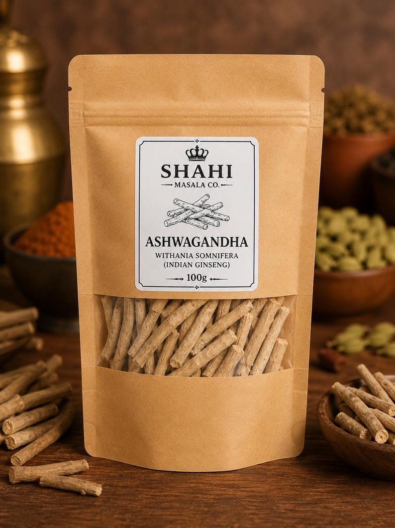 K&ouml;nnte beinhalten: Ein wiederverschlie&szlig;barer Beutel aus beigem Kraftpapier mit Ashwagandha-Wurzeln. Das wei&szlig;e Etikett tr&auml;gt den Text SHAHI MASALA CO., ASHWAGANDHA, WITHANIA SOMNIFERA (INDIAN GINSENG) und 100g. Ein Sichtfenster zeigt die hellbraunen Wurzelst&uuml;cke.
