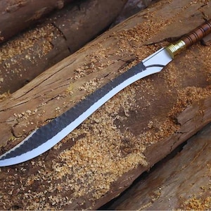 Op de afbeelding: Een gebogen zwaard met een donker, getextureerd, handgesmeed stalen lemmet en een gepolijste zilverkleurige snede. Het handvat is gemaakt van bruin hout met horizontale ribbels, geaccentueerd door goudkleurige metalen ringen.