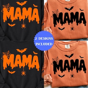 Op de afbeelding: Twee sweaters met ronde hals, één zwart en één oranje, elk met de tekst MAMA in een druipend lettertype. De ontwerpen bevatten grafische illustraties van vleermuizen, een spinnenweb en een hangende spin. De oranje sweater heeft zwarte graphics, de zwarte sweater heeft oranje graphics.