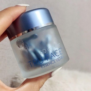 Pu&ograve; includere: Un barattolo in vetro smerigliato con coperchio blu metallizzato contenente capsule blu. L'etichetta riporta il logo Nu Skin e la scritta ageLOC TRU FACE ESSENCE ULTRA in blu. Il contenitore ha una forma cilindrica e una finitura semitrasparente.