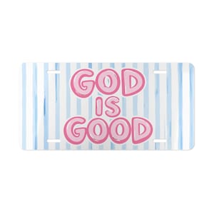 May include: A rectangular license plate featuring a light blue and white vertical striped background. The text GOD IS GOOD is printed in large, bold, bubble-style pink letters with a darker pink outline centered on the plate surface.