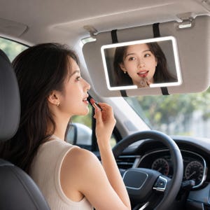 以下が含まれることがあります： LEDライト付きの長方形の車用サンバイザーミラー。黒いストラップで車両のサンバイザーに取り付けられており、反射ガラス表面の下部中央にタッチ式の電源ボタンが配置されています。