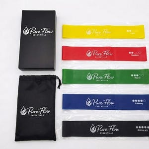 May include: A set of five resistance bands in yellow, red, green, blue, and black, each labeled Pure Flow Essentials with varying resistance levels. Includes a black storage bag and a black rectangular box, both featuring the Pure Flow Essentials logo.