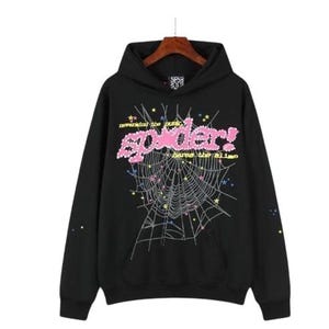 K&ouml;nnte beinhalten: Ein schwarzer Kapuzenpullover mit einer gro&szlig;en Grafik eines Spinnennetzes und bunten Sternen. Der Text "nevermind the punk, spider!" und "heros the slime" ist in Pink und Gelb gedruckt. Die &Auml;rmel haben kleine, bunte Sternakzente.