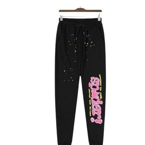 K&ouml;nnte beinhalten: Schwarze Jogginghose mit Kordelzug in der Taille, mehrfarbigen Farbspritzern im oberen Vorderbereich und einer gro&szlig;en rosa Grafik auf dem linken Bein mit der Aufschrift "sp5der!" sowie dem gelben Text "nevermind the punk, here the alien".