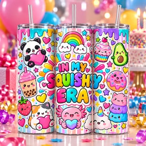 May include: Three cylindrical tumblers with clear straws featuring a colorful pattern of kawaii-style characters, hearts, stars, and rainbows. The center tumbler displays the text "IN MY SQUISHY ERA" in bold, multi-colored bubble letters.