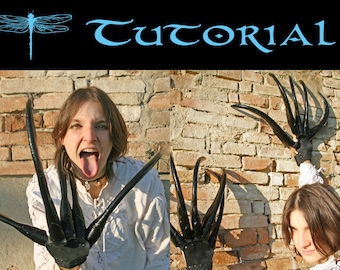 May include: Two people wearing black claw gloves with long, sharp, black claws. The claws are made of a flexible material and are attached to the back of the hand. The gloves are worn with white shirts. The people are standing in front of a brick wall.