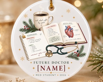 May include: A round white ceramic ornament featuring a coffee mug labeled med school nights big goals, an open textbook with medical notes and a heart illustration, a spiral notebook on pathophysiology, a stethoscope, and text reading FUTURE DOCTOR [NAME] MED STUDENT 2026.