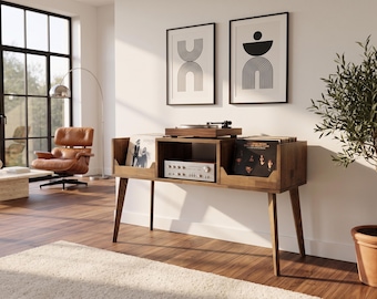 May include: A dark wood record console featuring a top surface for a turntable, a central shelf for an amplifier, and two side compartments for vinyl records. The console stands on four tapered legs and has a rectangular frame with open storage.