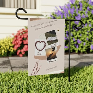 May include: A rectangular garden flag on a black metal stand featuring a beige background with the text As for me and my house, we will serve the LORD, Joshua 24:15, and images of a crown of thorns, an open book, and reaching hands.