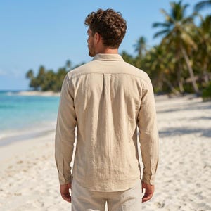 Pode incluir: Uma camisa de manga comprida com bot&otilde;es em cor bege claro. A camisa apresenta um colarinho cl&aacute;ssico, um jugo traseiro com uma prega central e punhos abotoados. O tecido tem uma trama texturizada vis&iacute;vel e a camisa &eacute; usada por fora.