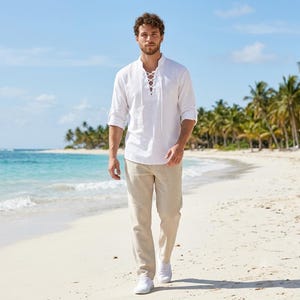 Pode incluir: Uma camisa branca de manga comprida com fecho frontal de atacadores e decote sem colarinho, combinada com cal&ccedil;as bege. A camisa apresenta mangas arrega&ccedil;adas e um tecido texturizado, enquanto as cal&ccedil;as t&ecirc;m um corte reto e tom neutro.