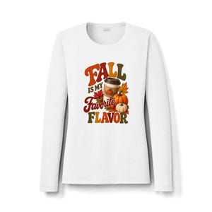 May include: A white long-sleeve shirt featuring a graphic print with the text FALL IS MY FAVORITE FLAVOR in retro-style lettering. The design includes a coffee cup, orange and white pumpkins, and colourful autumn leaves in shades of red and gold.