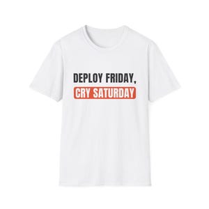May include: A white short-sleeved t-shirt featuring the black text "DEPLOY FRIDAY," followed by the text "CRY SATURDAY" in white letters inside a red rectangular box centred on the chest area of the garment.
