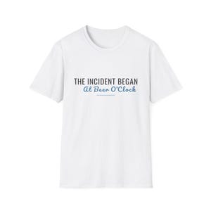 May include: A white short-sleeved t-shirt featuring the black text THE INCIDENT BEGAN and the blue cursive text At Beer O'Clock with a horizontal blue line underneath the text centered on the chest area of the garment.