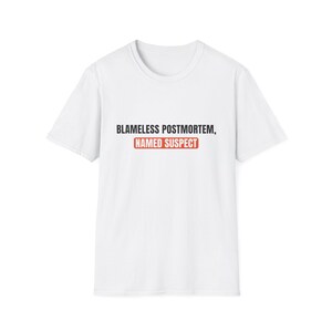 Puede incluir: Una camiseta blanca de manga corta con el texto negro BLAMELESS POSTMORTEM, seguido del texto NAMED SUSPECT en letras blancas dentro de un recuadro rectangular rojo centrado en la zona del pecho de la prenda.
