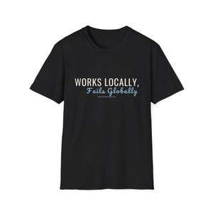May include: A black short-sleeved t-shirt featuring the white text "WORKS LOCALLY," on the top line and the light blue script text "Fails Globally" on the second line, with a thin light blue horizontal line underlined beneath the second phrase.