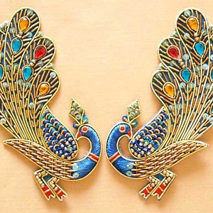 May include: Two embroidered peacock appliques with blue, gold, and red accents. The peacocks have detailed feathers and are perfect for adding a touch of elegance to any project.