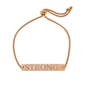 Könnte beinhalten: Ein verstellbares Armband in Roségold-Optik mit einer feinen Boxkette und einem zentralen rechteckigen Metallsteg. Der Steg ist mit dem Wort STRONG in einer Serifenschrift graviert. Das Armband verfügt über einen Schiebeverschluss.