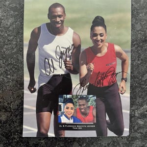May include: A signed photograph featuring Al Joyner in a white tank top and black shorts, and Florence Griffith Joyner in a red tank top and black leggings. A smaller inset photo shows them together with the text AL & FLORENCE GRIFFITH JOYNER TEAM ION.