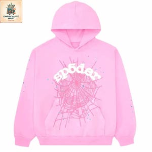 May include: A bright pink hooded sweatshirt featuring a large, centered graphic of a spider web in a darker shade of pink. The word "sp5der" is printed in white, bold, rounded letters across the top of the web design, with small scattered dots.