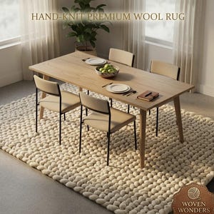 Puede incluir: Una alfombra grande de lana premium tejida a mano en color crema con un tejido grueso y texturizado. La alfombra está colocada bajo una mesa de comedor de madera clara con cuatro sillas. El texto HAND-KNIT PREMIUM WOOL RUG y WOVEN WONDERS es visible.
