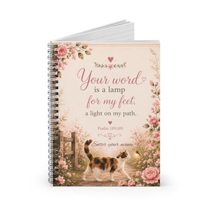 Puede incluir: Un cuaderno de espiral con un gato calicó caminando por un sendero rodeado de flores rosas y una valla de madera. La portada muestra el texto: Your word is a lamp for my feet, a light on my path. Psalm 119:105. Enter your name.
