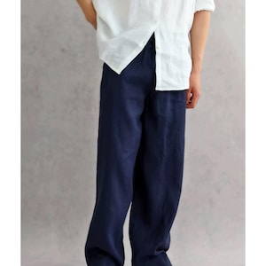 May include: A pair of loose-fitting navy blue trousers with a straight-leg silhouette and a simple waistband, paired with a white button-down shirt and white sneakers. The trousers feature a plain, solid-colored fabric with a relaxed, comfortable fit.